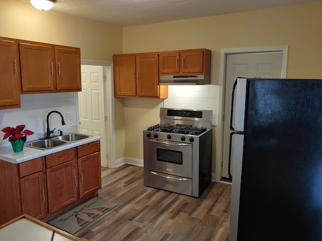 kitchen with tasteful backsplash, sink, dark hardwood / wood-style floors, stainless steel range with gas cooktop, and fridge