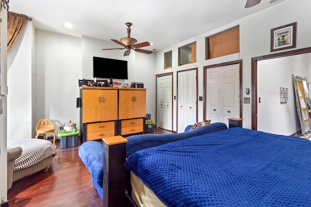 bedroom with two closets, ceiling fan, and dark wood-type flooring