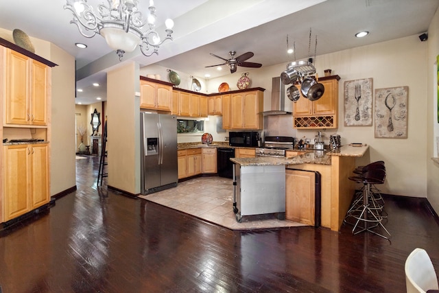 kitchen featuring black appliances, ceiling fan with notable chandelier, wall chimney range hood, light wood-type flooring, and decorative light fixtures