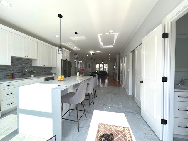 kitchen featuring white cabinets, black fridge with ice dispenser, decorative light fixtures, and a kitchen island