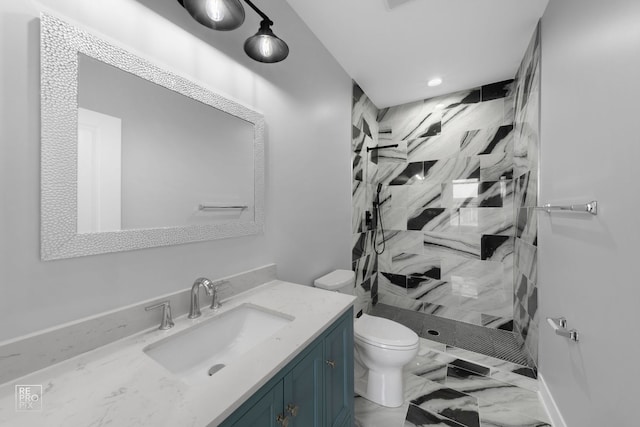 bathroom featuring toilet, a tile shower, and vanity