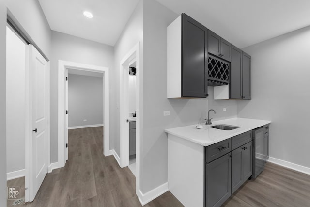 kitchen with gray cabinetry, stainless steel dishwasher, sink, and dark wood-type flooring