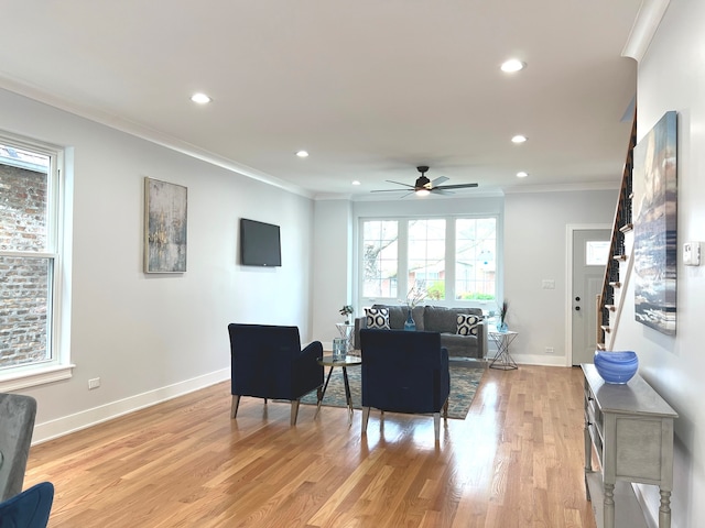 living room featuring ceiling fan, light hardwood / wood-style flooring, and ornamental molding