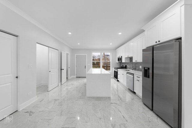 kitchen with sink, a kitchen island, tasteful backsplash, white cabinets, and appliances with stainless steel finishes