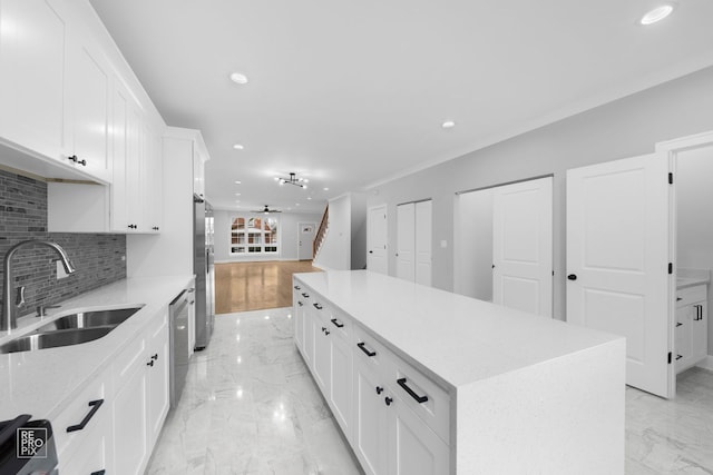 kitchen with white cabinetry, a center island, sink, stainless steel appliances, and decorative backsplash