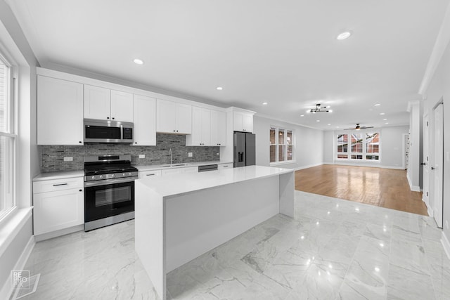 kitchen with ceiling fan, a center island, white cabinetry, and stainless steel appliances