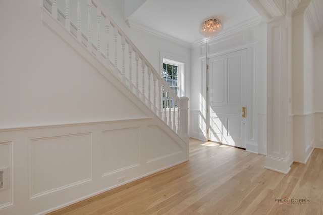 entryway with an inviting chandelier, ornamental molding, and light wood-type flooring