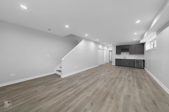 unfurnished living room with light hardwood / wood-style floors, beverage cooler, and sink