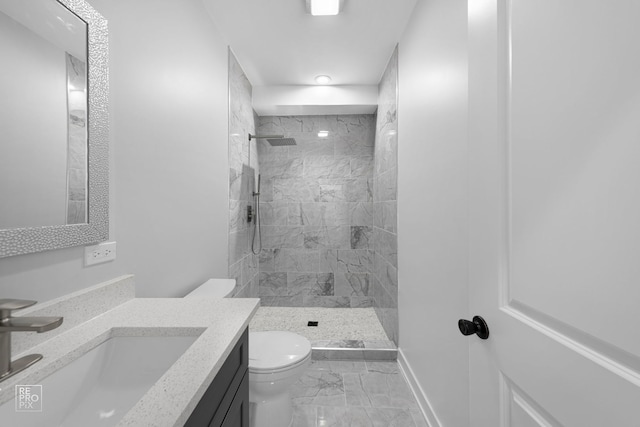 bathroom with vanity, toilet, and tiled shower