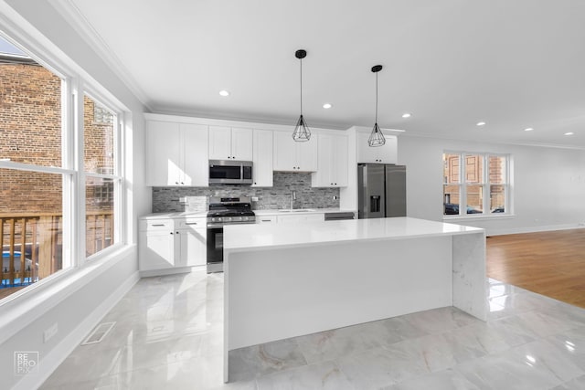 kitchen featuring white cabinets, decorative light fixtures, a center island, and stainless steel appliances