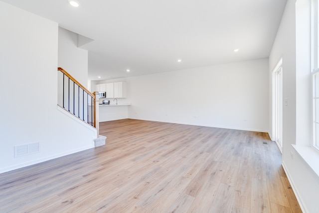 unfurnished living room featuring sink and light hardwood / wood-style flooring