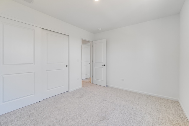 unfurnished bedroom with light colored carpet and a closet