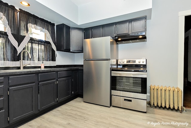 kitchen featuring appliances with stainless steel finishes, light wood-type flooring, radiator, and sink