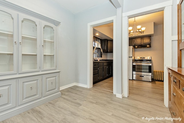 interior space with stainless steel range, radiator heating unit, hanging light fixtures, a notable chandelier, and light wood-type flooring