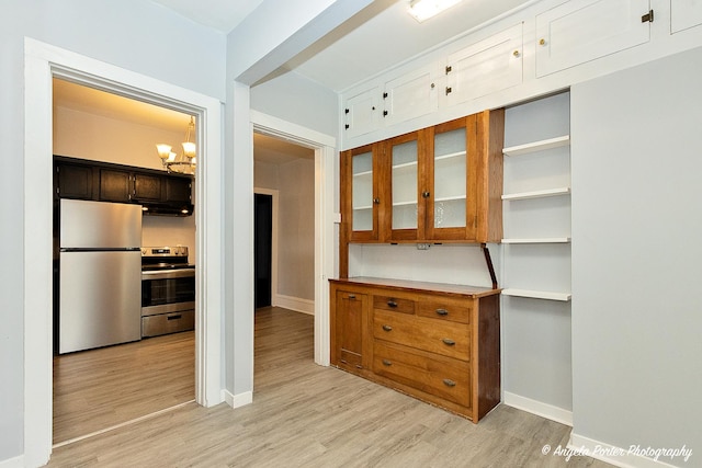 kitchen with appliances with stainless steel finishes, light hardwood / wood-style floors, and an inviting chandelier