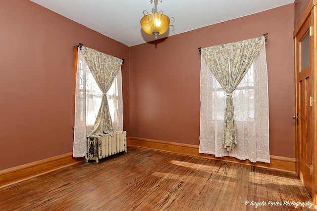 unfurnished room with a wealth of natural light, hardwood / wood-style flooring, and radiator