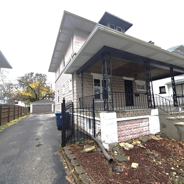 view of side of home with a porch, a garage, and an outbuilding