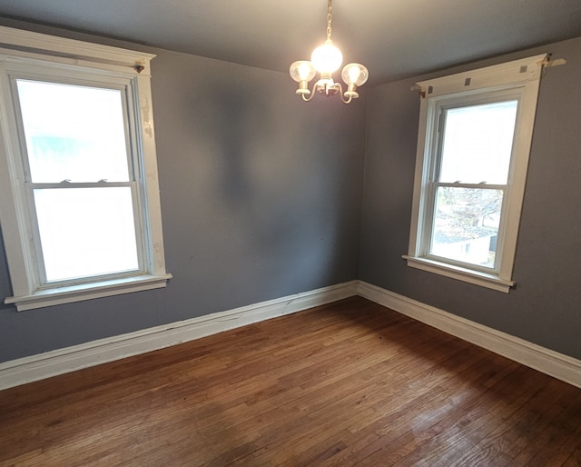 empty room with hardwood / wood-style floors and a notable chandelier