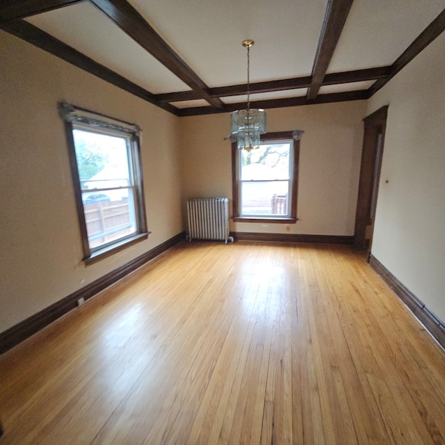 unfurnished dining area featuring radiator heating unit, light wood-type flooring, an inviting chandelier, and a wealth of natural light