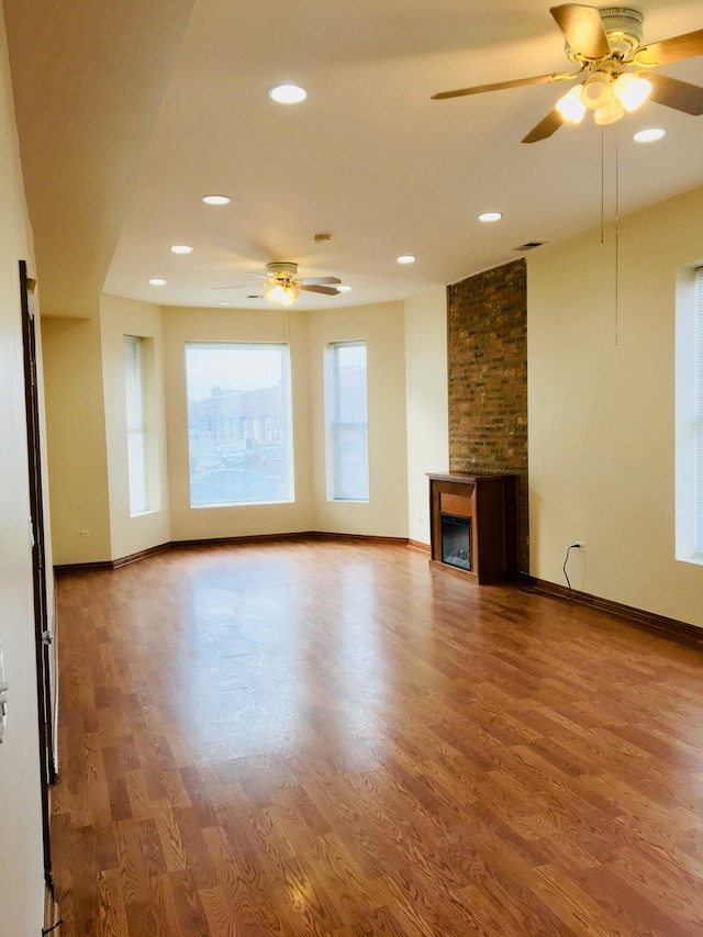 unfurnished living room featuring a fireplace, hardwood / wood-style floors, and ceiling fan