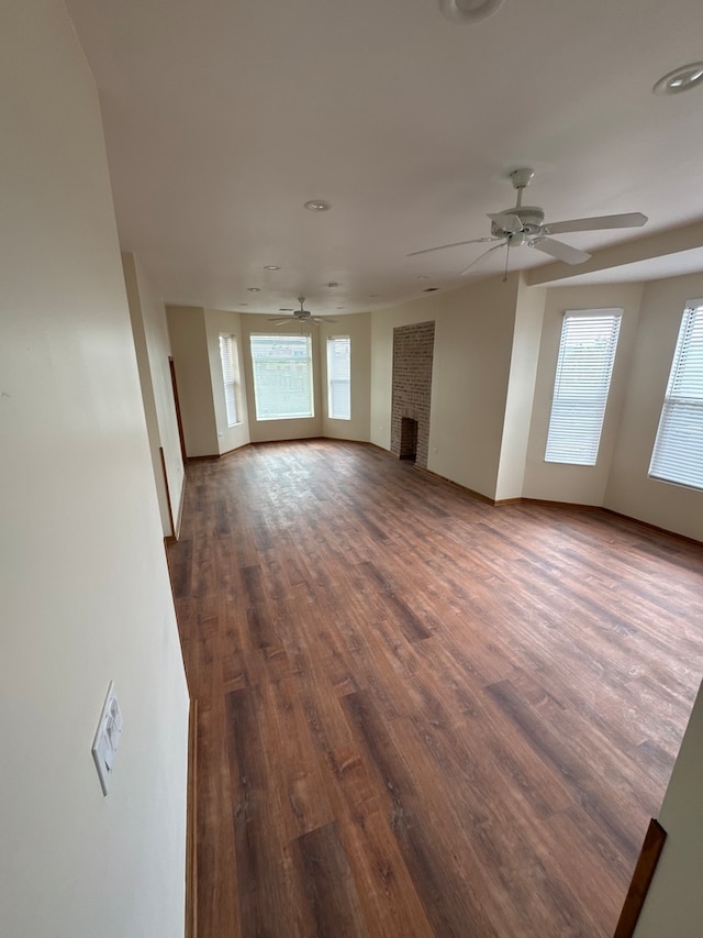 unfurnished living room featuring ceiling fan, dark hardwood / wood-style flooring, and a fireplace