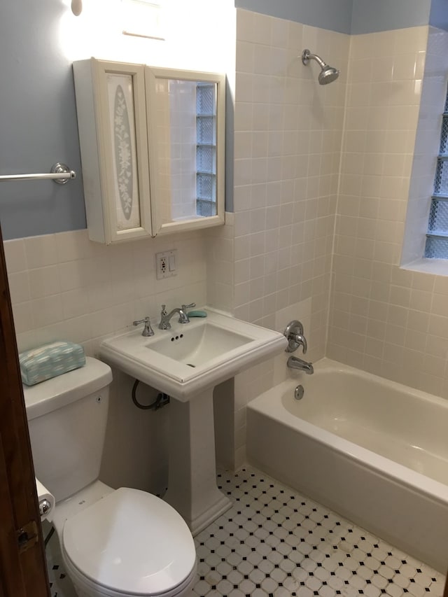 bathroom with tile patterned flooring, decorative backsplash, toilet, and tiled shower / bath