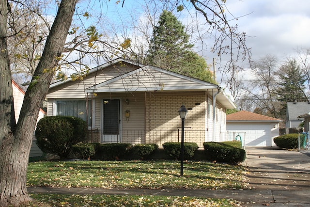 bungalow with a front yard, a garage, and an outdoor structure