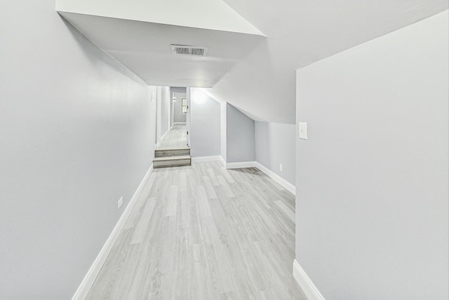 additional living space with light hardwood / wood-style flooring and lofted ceiling