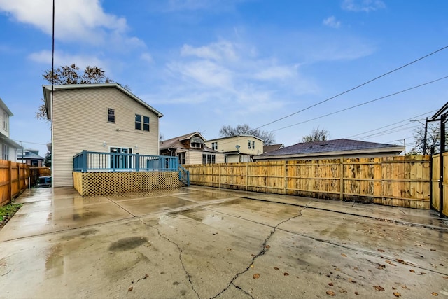 back of house with a wooden deck and a patio