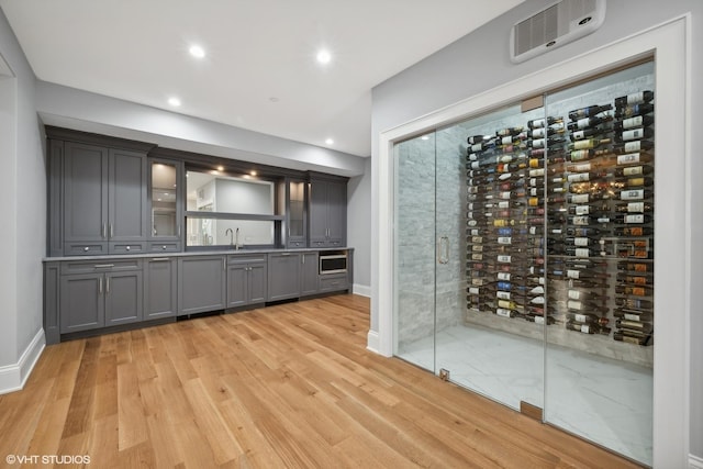 wine area featuring light wood finished floors, recessed lighting, a sink, electric panel, and baseboards