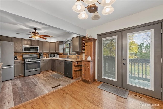 kitchen with decorative backsplash, appliances with stainless steel finishes, light hardwood / wood-style floors, and french doors