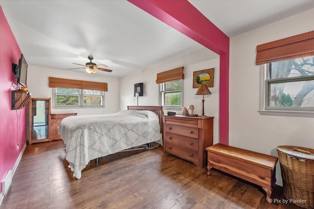 bedroom featuring ceiling fan, dark hardwood / wood-style flooring, and multiple windows