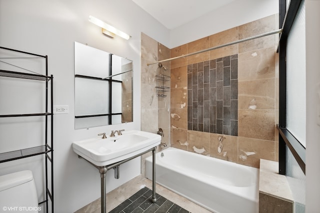 bathroom featuring tile patterned flooring, tiled shower / bath combo, and toilet