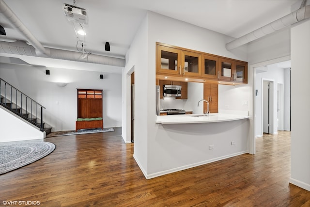 kitchen featuring kitchen peninsula, appliances with stainless steel finishes, dark hardwood / wood-style flooring, sink, and beam ceiling