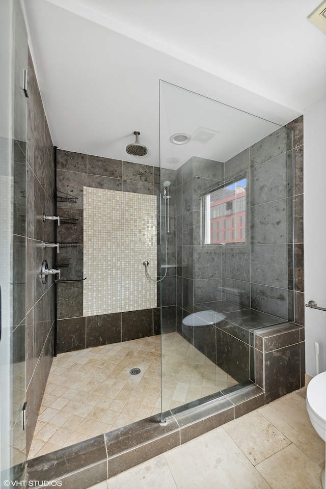 bathroom featuring toilet, tile patterned floors, and a shower with shower door