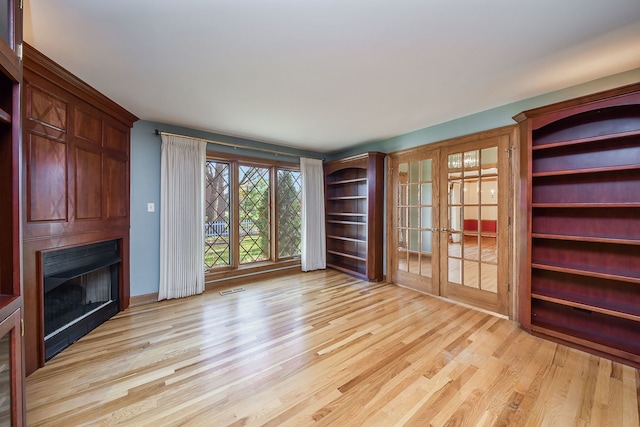 unfurnished living room featuring light wood-type flooring and french doors