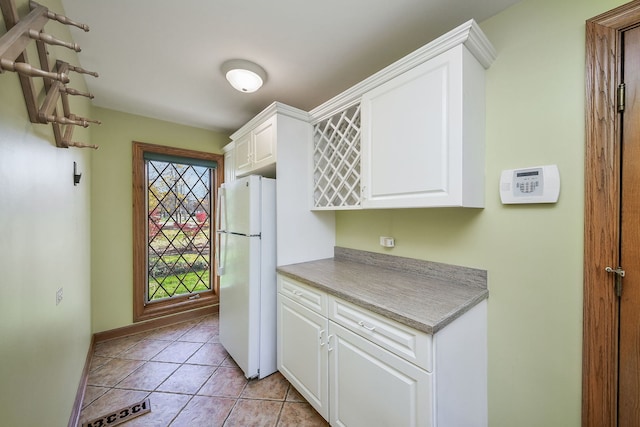 kitchen featuring white cabinets, white refrigerator, and light tile patterned floors