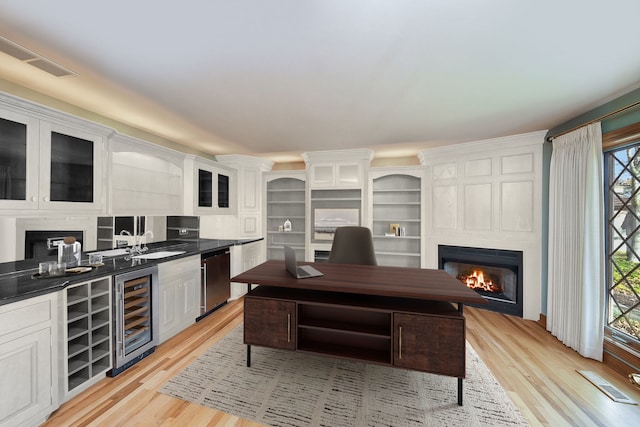 kitchen featuring a healthy amount of sunlight, white cabinetry, a fireplace, and beverage cooler