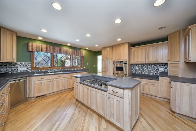 kitchen with sink, a center island, stainless steel appliances, light brown cabinets, and light wood-type flooring