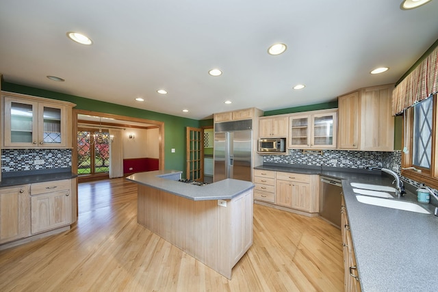 kitchen featuring light brown cabinets, built in appliances, a center island, and light hardwood / wood-style floors