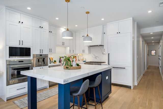 kitchen featuring pendant lighting, light wood-type flooring, a center island, and white cabinetry