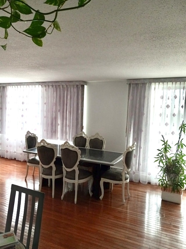 dining room with hardwood / wood-style floors and a textured ceiling