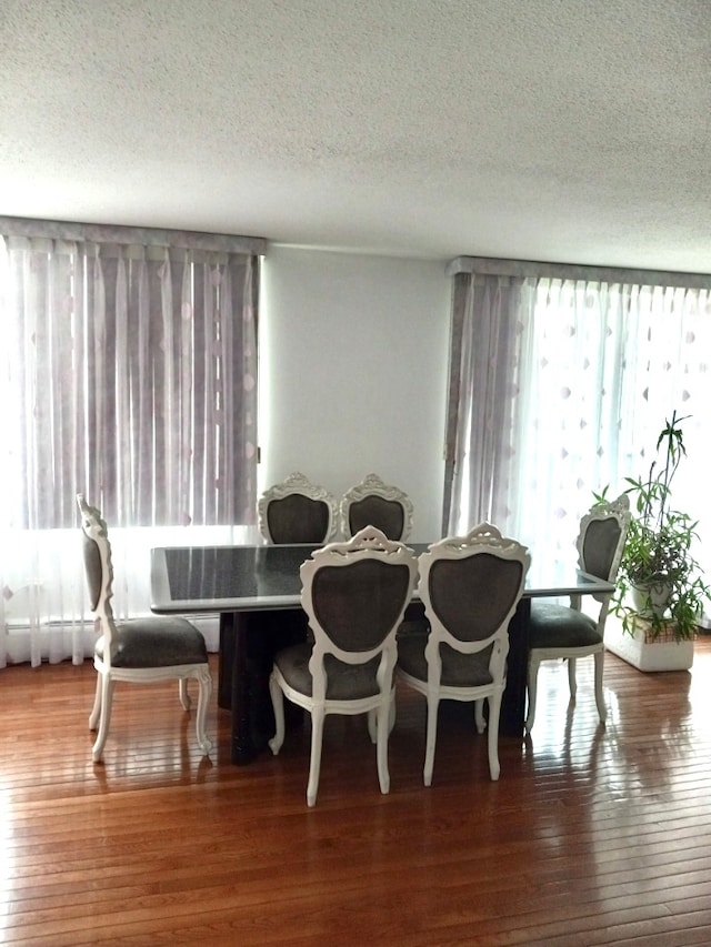 dining space featuring hardwood / wood-style flooring and a textured ceiling