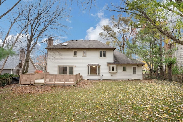 rear view of house with a lawn and a wooden deck