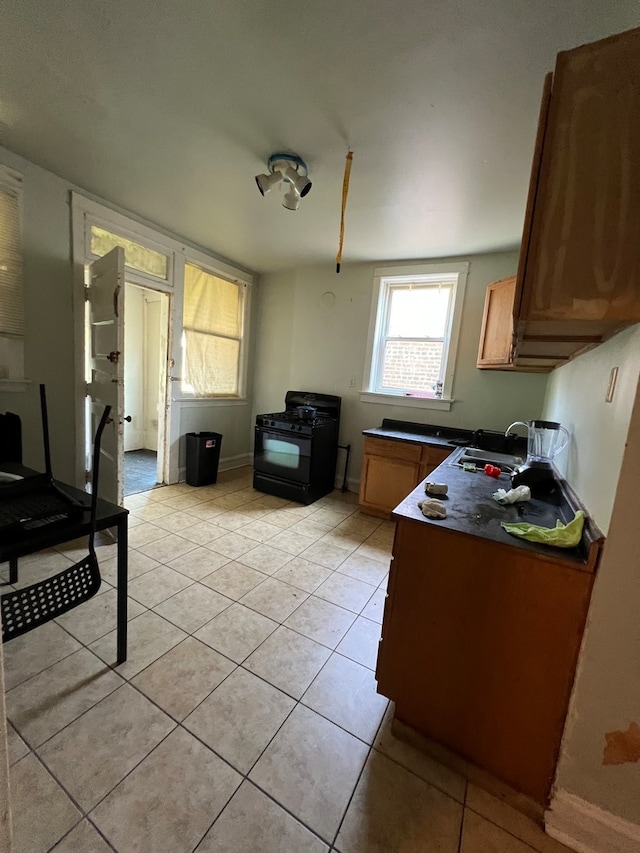 kitchen featuring black gas range, light tile patterned floors, and sink