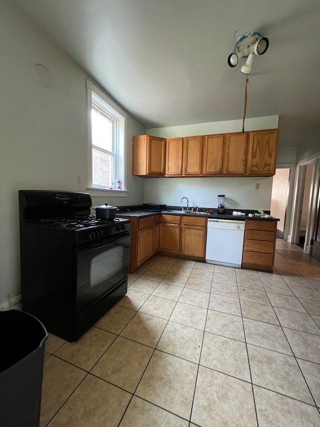 kitchen featuring lofted ceiling, white dishwasher, black gas stove, sink, and light tile patterned flooring