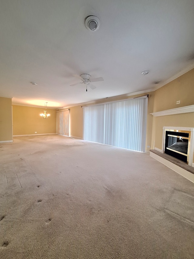 unfurnished living room with carpet, ceiling fan with notable chandelier, and ornamental molding