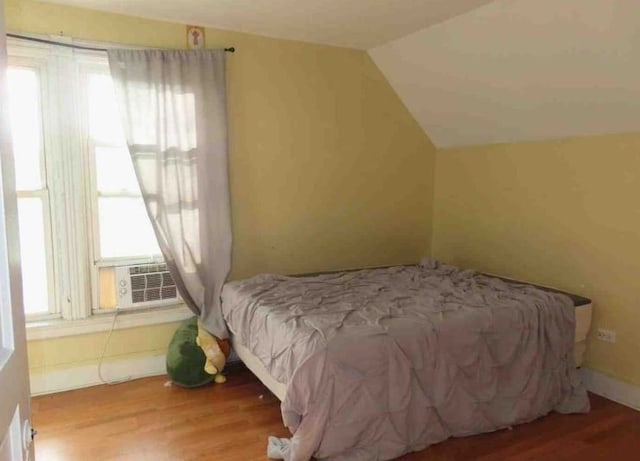 bedroom with cooling unit, wood-type flooring, and lofted ceiling