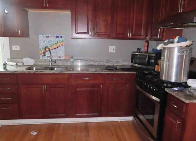 kitchen with light stone countertops, sink, stainless steel appliances, and light hardwood / wood-style flooring