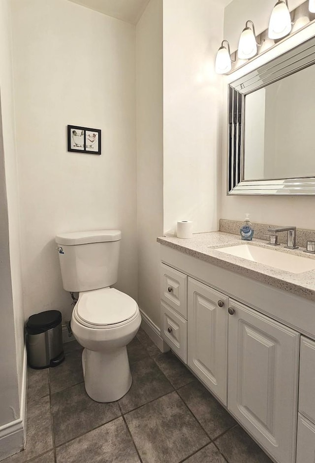 bathroom featuring baseboards, vanity, and toilet